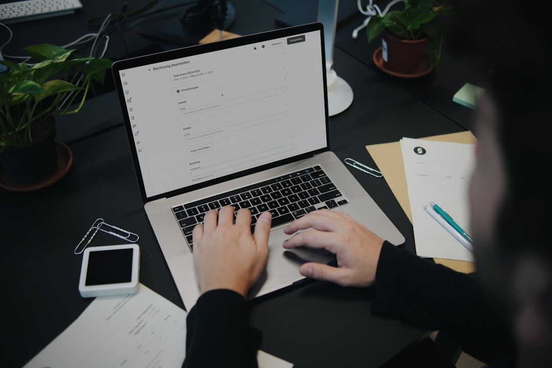 En person arbetar med en faktura på en bärbar dator vid ett skrivbord.